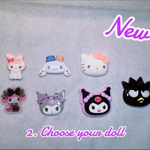 May include: A collection of seven colorful character dolls, including a pink bunny, a white cat with a pink bow, and a black character with yellow accents. The text "New!" and "2. Choose your doll" are also visible.