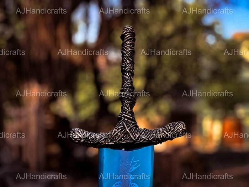 May include: A close-up of a sword with a black, braided handle and a blue blade. The blade has a decorative design etched into it.