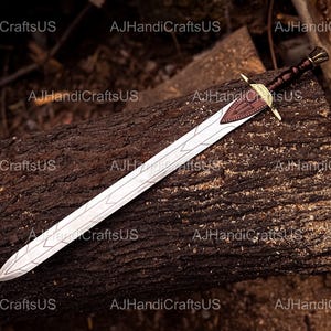 May include: A decorative sword with a silver blade and a brown leather-wrapped handle. The sword features a gold-colored crossguard and a brown leather accent on the hilt. The sword is resting on a dark brown log.