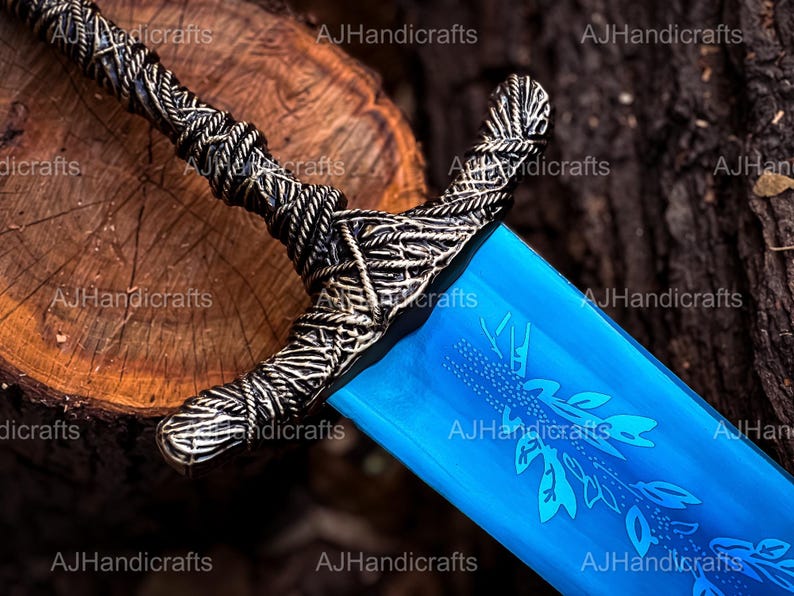May include: A blue sword with a silver handle and a decorative design. The sword is lying on a wooden surface.