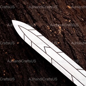 May include: A decorative, white sword blade with black geometric designs. The blade is set against a dark brown, textured wooden surface. The text "AJHandiCraftsUS" is visible in the background.