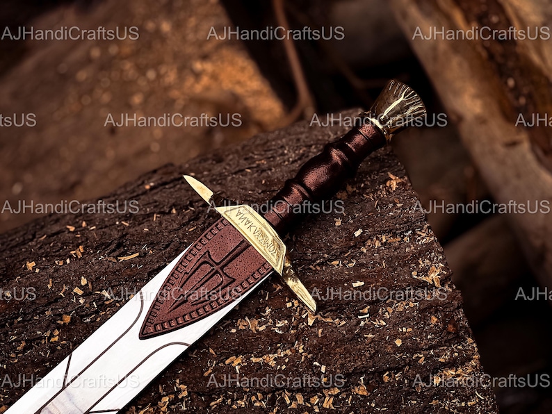 May include: A detailed image of a decorative sword with a brown leather-wrapped handle and a gold-colored hilt. The blade is silver with a brown leather guard featuring a trident design. The sword rests on a textured wooden surface.