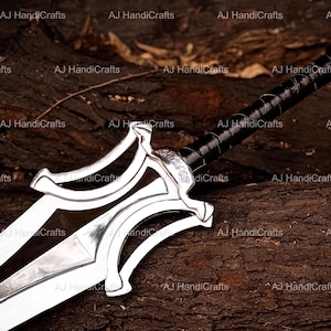 May include: A silver-colored metal sword featuring a double-edged blade with a central ridge and a complex, curved crossguard. The handle is wrapped in black material, and the pommel is a simple circular metal cap at the end of the grip.