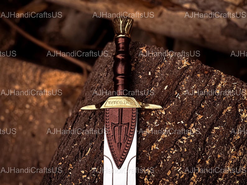May include: A detailed image of a sword with a brown handle and a gold-colored hilt. The blade is silver with a brown emblem. The sword rests on a textured, dark brown surface. The text "&Psi;&Eta;&Nu;&Kappa;&Nu;&Alpha;&Sigma;&Kappa;&Omicron;" is visible on the hilt.