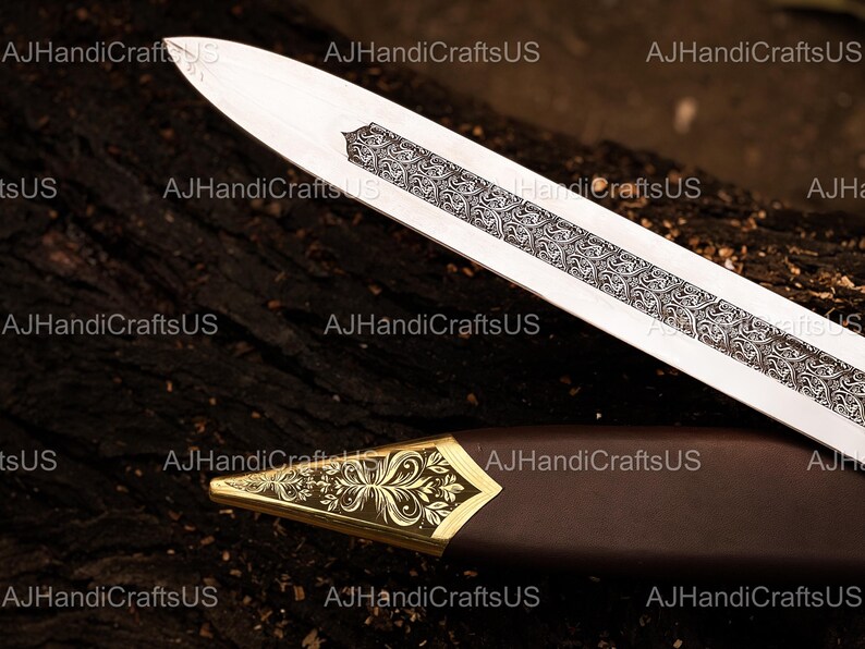 May include: A detailed image of a sword with a silver blade and ornate engravings. The hilt is encased in a brown sheath with a gold-colored, decorative tip. The text "AJHandiCraftsUS" is visible in the image.