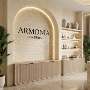 Op de afbeelding: Interieur van een spa met de naam "ARMONIA SPA DUBAI" in zwarte letters op een beige muur. De ruimte beschikt over houten kasten, planken met decoratieve items en potplanten. Het algehele ontwerp is minimalistisch en elegant.