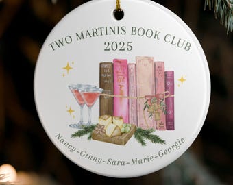 May include: White ceramic Christmas ornament with gold string, featuring the text "TWO MARTINIS BOOK CLUB 2025". The ornament has a watercolor illustration of books, martinis, and names. Festive holiday decor.