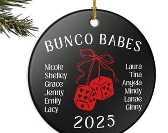 May include: A black ceramic ornament with gold string, featuring the text "BUNCO BABES" and a pair of red dice. Names of the group members are listed around the dice, with the year "2025" at the bottom. The ornament hangs from a Christmas tree branch.