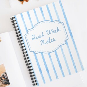 Könnte beinhalten: Ein spiralgebundenes Notizbuch mit hellblau-weißem vertikalem Streifenmuster und einem zentralen dekorativen Etikett mit der Aufschrift Rush Week Notes in blauer Schreibschrift, dazu eine goldene Metallklammer und eine Sonnenbrille.