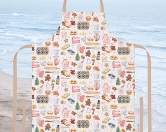 May include: A white apron with a repeating pattern of baking-themed illustrations. The design includes gingerbread men, rolling pins, baking pans, and other kitchen tools in red, pink, and brown. The apron has a beige neck strap and waist ties.