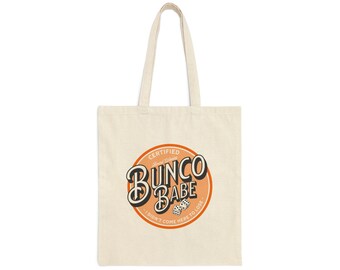 Op de afbeelding: Een beige canvas draagtas met een oranje cirkellogo met de tekst "Certified Bungo Babe - I didn't come here to lose".
