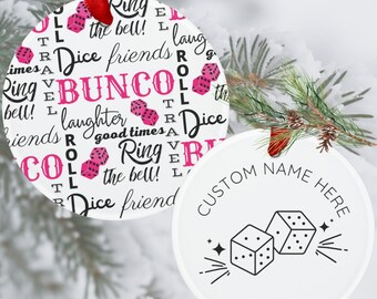 May include: White round Christmas ornament with pink and black text that says "Ring the bell! Dice friends Bunco laughter good times Ring the bell! Dice friend" and pink dice. A second white round ornament with black text that says "Custom Name Here" and a black outline of two dice with stars. The year 2023 is printed below the dice.