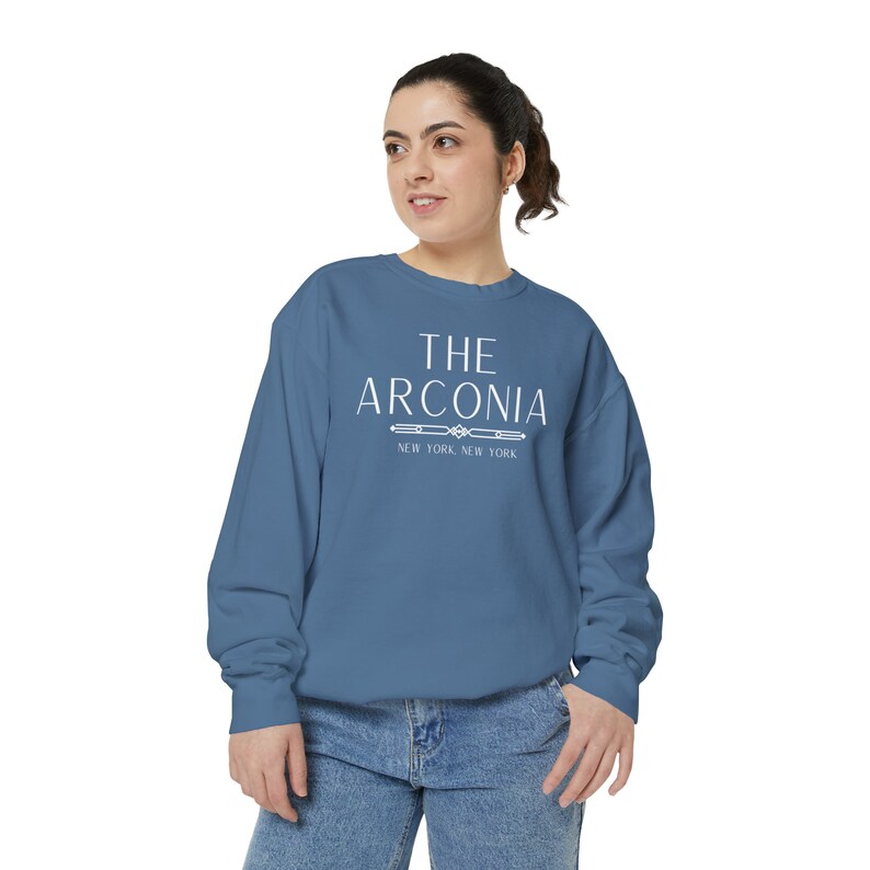 Pode incluir: Uma camisa de moletom azul com texto branco que diz "THE ARCONIA NEW YORK, NEW YORK".