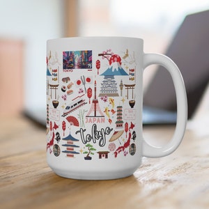 May include: White ceramic mug with a colorful design featuring Japanese landmarks, including Mount Fuji, the Tokyo Skytree, and a red torii gate. The mug also features a red and white Japanese flag, cherry blossoms, and the text "Japan Tokyo".