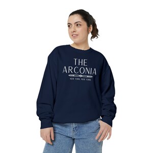 Pode incluir: Uma camisa de moletom azul marinho com texto branco que diz "THE ARCONIA NEW YORK, NEW YORK".
