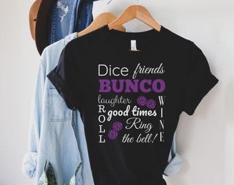 Könnte beinhalten: Schwarzes T-Shirt mit weißem Text, der "Dice friends BUNCO laughter R good times L Ring the bell! E" lautet, mit lila Würfelgrafiken.