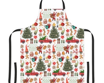 May include: A white Christmas-themed apron with a red truck, Christmas trees, candy canes, gingerbread men, and other festive elements. The text "Santa's Toy Factory" is repeated throughout the design.