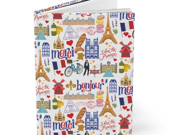 May include: A white journal cover featuring a colourful pattern of French icons, including the Eiffel Tower, croissants, and the words "bonjour", "merci", and "vive la France".