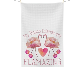Peut inclure: Une serviette de cuisine blanche avec le texte "My Bunco friends are FLAMAZING" en lettres roses. Deux flamants roses avec des fleurs roses se font face avec un cœur rose entre eux. Deux dés roses sont de chaque côté des flamants roses.