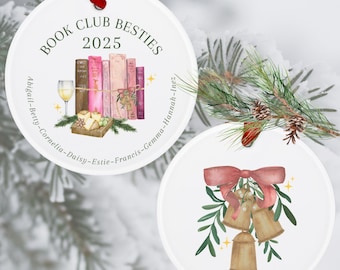 Pode incluir: Dois enfeites de Natal redondos brancos. O primeiro enfeite apresenta uma pilha de livros com uma taça de vinho e o texto "Book Club Besties 2025" e uma lista de nomes. O segundo enfeite apresenta um grupo de sinos dourados com um laço vermelho e folhas verdes.