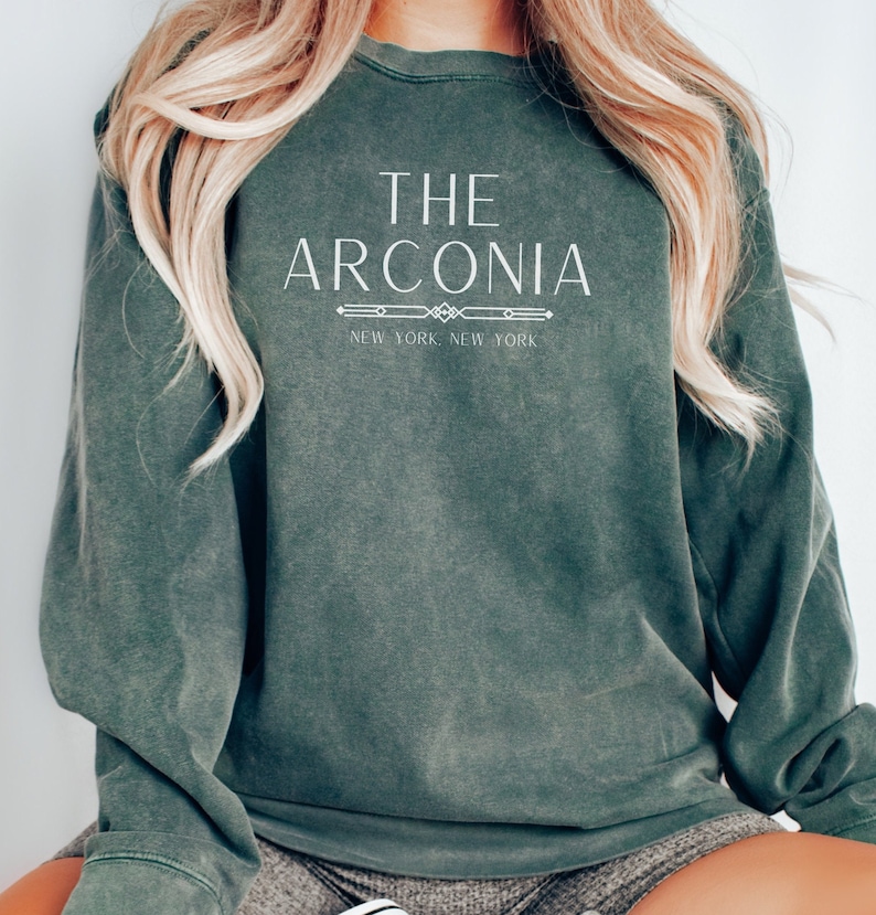 Pode incluir: Uma camisa de moletom verde escura com o texto "THE ARCONIA NEW YORK NEW YORK" impresso em branco.