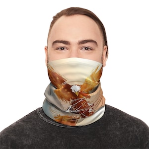 May include: A neck gaiter featuring a detailed illustration of a bald eagle with outstretched wings. The eagle is depicted in shades of brown, gold, and white against a light background. The neck gaiter is worn by a person.