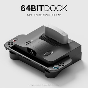 Könnte beinhalten: Eine schwarze 64BITDOCK-Station für Nintendo Switch 1/2 im Retro-Konsolendesign mit einem Kartenschacht auf der Oberseite, Lüftungsschlitzen und integrierten Controller-Halterungen an den Seiten. Das Gerät zeigt den Text 64BITDOCK NINTENDO SWITCH 1/2.