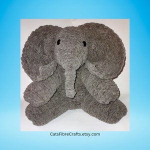 Op de afbeelding: Een grijze, pluche olifant met grote oren, een slurf en zwarte ogen. De handgemaakte olifant zit rechtop. De Etsy shopnaam, CatsFibreCrafts.etsy.com, is zichtbaar onderaan.
