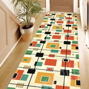 May include: A geometric runner rug with a white background and black, red, yellow, and green squares. The rug has a modern design.