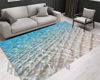 May include: A blue and white area rug with a design that looks like the ocean floor. The rug is laid out on a light wood floor in a living room setting.