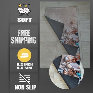 Pode incluir: Um tapete retangular com uma cena de praia com conchas e areia. O tapete tem 0,5 cm de espessura e tem um suporte antiderrapante. A imagem tamb&eacute;m inclui as palavras "SOFT" e "NON SLIP".