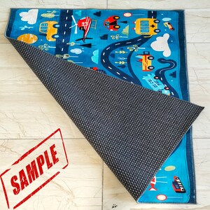 May include: A blue and yellow play mat with a road and various vehicles, including a helicopter, a school bus, and a car. The mat has a non-slip backing.
