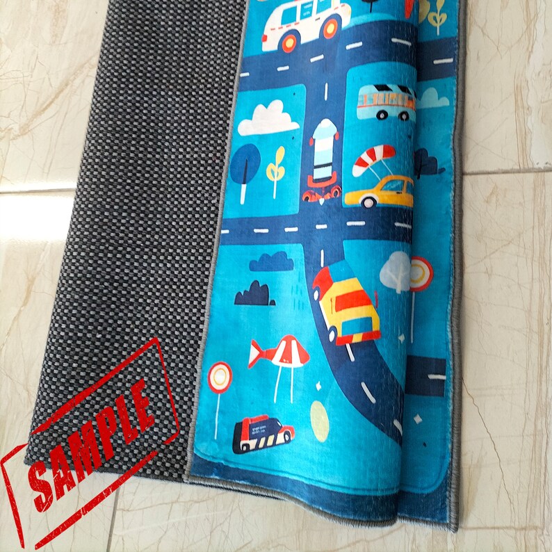 May include: A blue and gray play mat with a road and traffic signs design. The mat is rolled up and has a gray backing.