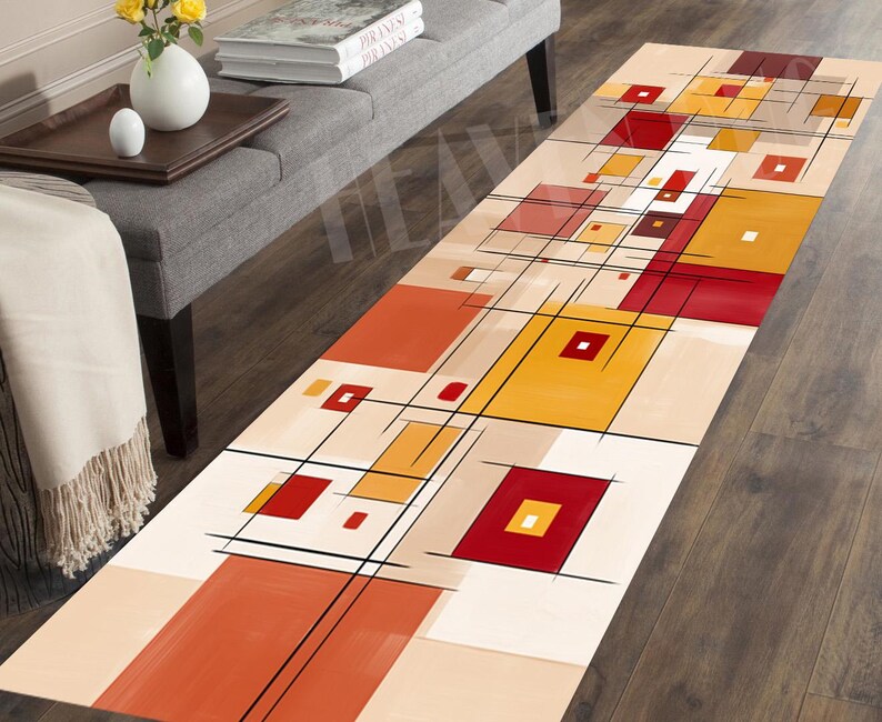 May include: A rectangular area rug with an abstract geometric design. The rug features a beige background with squares and rectangles in shades of red, orange, and yellow, outlined with black lines. The rug is placed on a dark wood floor.