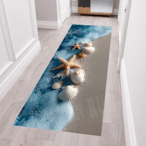 Puede incluir: Una alfombra de pasillo rectangular con una impresión de alta resolución de una orilla de playa arenosa. El diseño muestra olas azules del océano con espuma blanca sobre arena beige, decorado con varias conchas y estrellas de mar.
