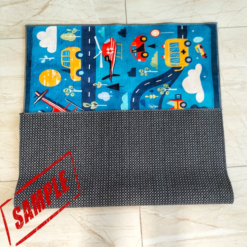 May include: A colorful play mat with a road, cars, a helicopter, and clouds. The mat has a gray non-slip backing.