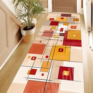 May include: A rectangular hallway rug with a geometric design. The rug features squares in shades of red, yellow, and orange, with black lines and a beige background. The word "HEAVEN" is visible on the rug.