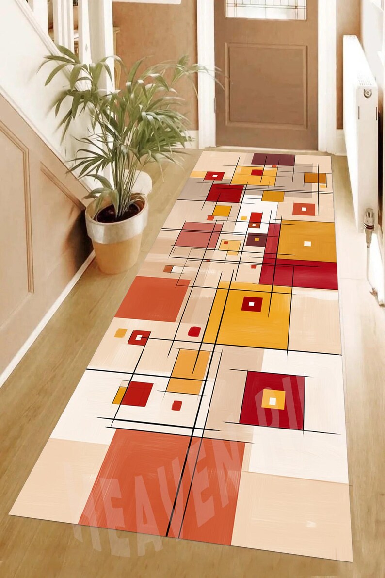 May include: A rectangular hallway rug with a geometric design. The rug features squares in shades of red, yellow, and orange, with black lines and a beige background. The word "HEAVEN" is visible on the rug.