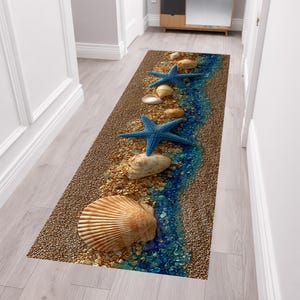 Peut inclure: Un tapis de couloir rectangulaire présentant une impression haute résolution d'un rivage sablonneux. Le motif comprend un ruisseau central de galets en verre bleu, deux étoiles de mer bleues et plusieurs coquillages beiges et blancs.