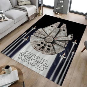Könnte beinhalten: Rechteckiger Star Wars Teppich mit dem Raumschiff Millennium Falcon und mehreren X-Wing-Jägern vor einem schwarz-weißen Hintergrund. Das Star Wars Logo ist deutlich zu sehen.