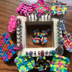 May include: A wooden loom with colorful rubber band bracelets in various patterns and colors. The loom has metal pegs and is used to create bracelets.