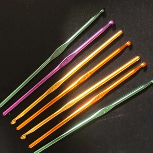May include: A set of six crochet hooks in various colors, including green, purple, and orange. The hooks are made of metal and have a smooth finish. The hooks are labeled with their sizes, which are 3.5 mm, 4.0 mm, 4.5 mm, 5.0 mm, 5.5 mm, and 6.0 mm.