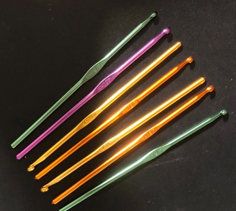 May include: A set of six crochet hooks in various colors, including green, purple, and orange. The hooks are made of metal and have a smooth finish. The hooks are labeled with their sizes, which are 3.5 mm, 4.0 mm, 4.5 mm, 5.0 mm, 5.5 mm, and 6.0 mm.