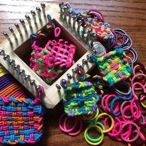 May include: A rainbow loom kit with a wooden loom, colorful rubber bands, and several completed loom band bracelets in various colors and patterns.