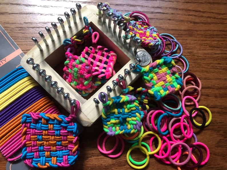 May include: A rainbow loom kit with a wooden loom, colorful rubber bands, and several completed loom band bracelets in various colors and patterns.