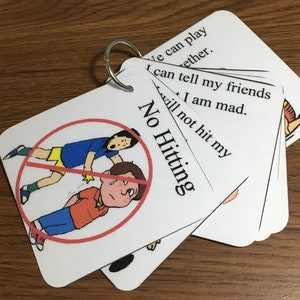 May include: A set of white flashcards on a metal ring, featuring the text "No Hitting" and illustrations of children. The cards also include phrases like "I can tell my friends" and "I will not hit my".