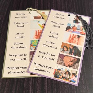 May include: Two rectangular paper bookmarks featuring a list of classroom rules including Stay in your seat, Raise your hand, Listen quietly, Follow directions, Keep hands to yourself, and Respect your classmates, with attached gold and gray tassels.