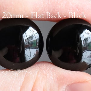 May include: Two black, flat-back, 20mm round glass cabochons.