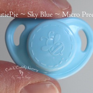 以下が含まれることがあります： ミツバチのデザインが施されたスカイブルーの哺乳瓶。マイクロ早産児用です。