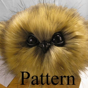 Op de afbeelding: Een pluche bruine en zwarte uil met grote zwarte ogen. Het speelgoed zit op een houten oppervlak met het woord "Pattern" erop.
